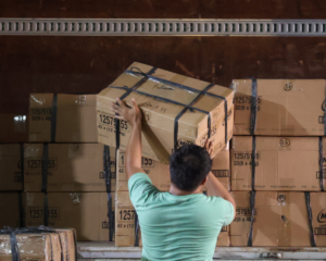 A worker handling stacked boxes of books for delivery to Culion, Palawan