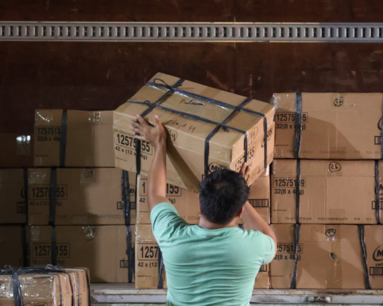 A worker handling stacked boxes of books for delivery to Culion, Palawan