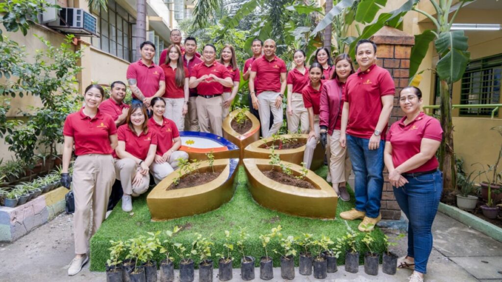Group photo of volunteers gathered around a sampaguita planting arrangement